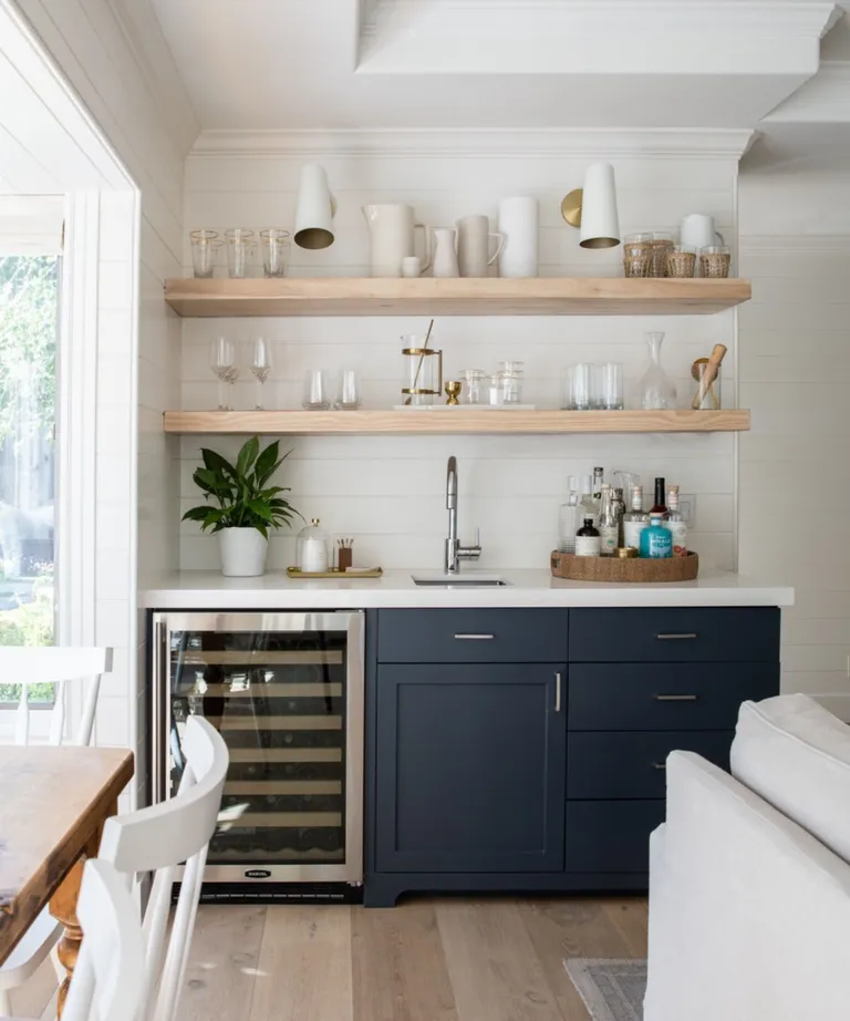 Home bar with lower cabinetry painted in Benjamin Moore Hale Navy paired with a ceaserstone countertop and open shelving