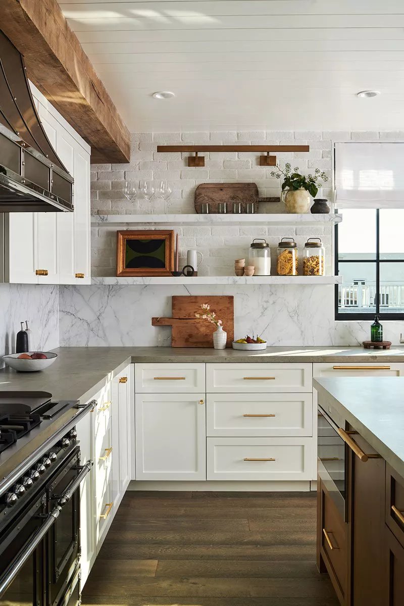 A kitchen with white cabinets, a white marble backsplash, and concrete countertops