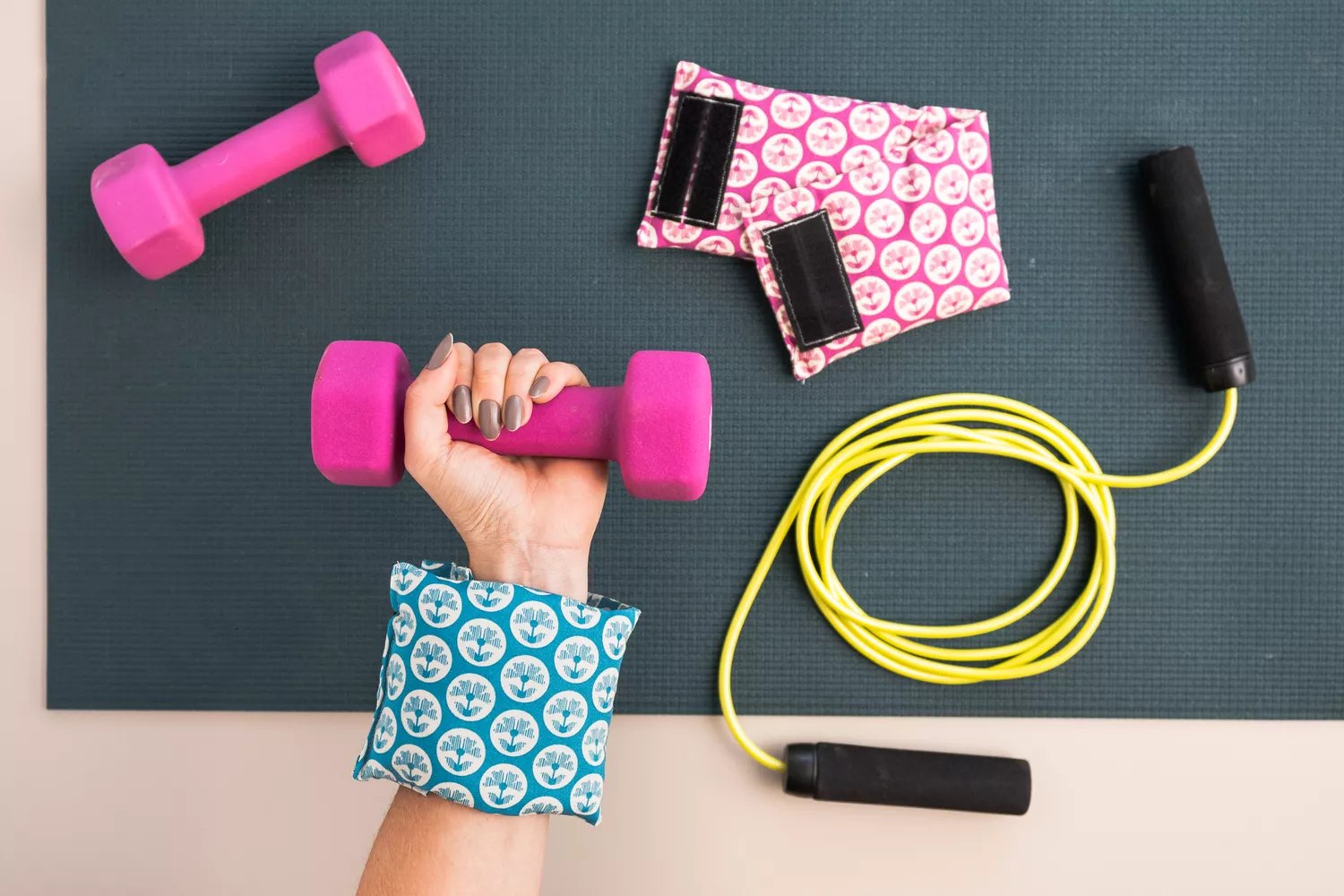 DIY wrist weights wrapped around while holding bright pink hand weights and jump rope