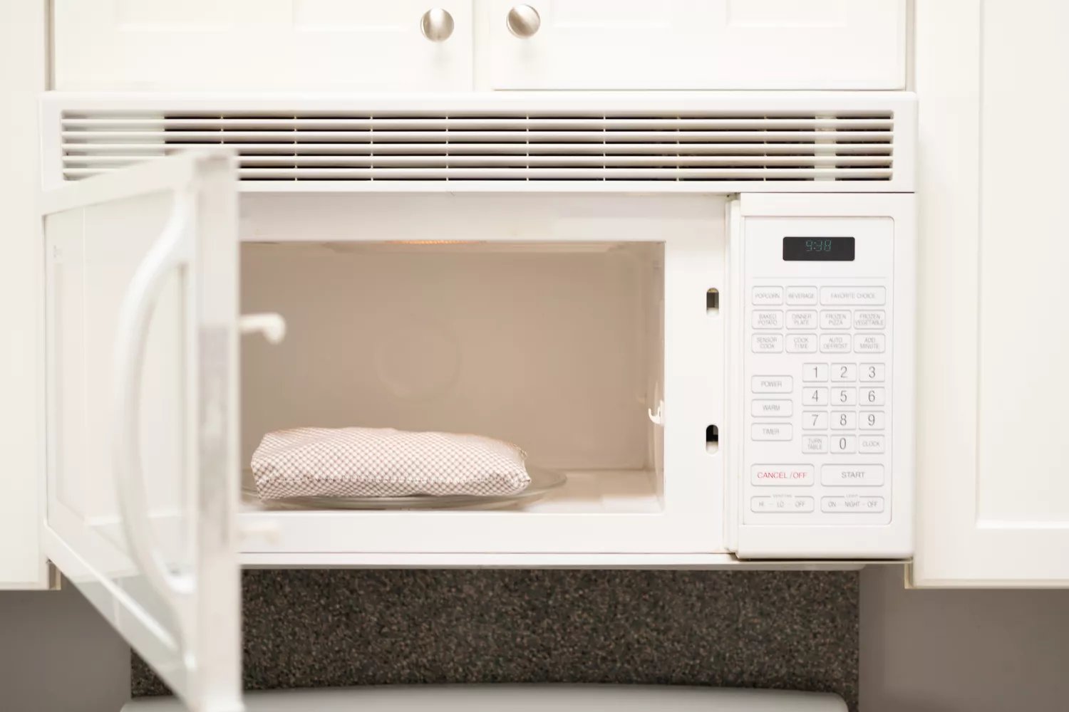 White microwave door open with heating pad inside